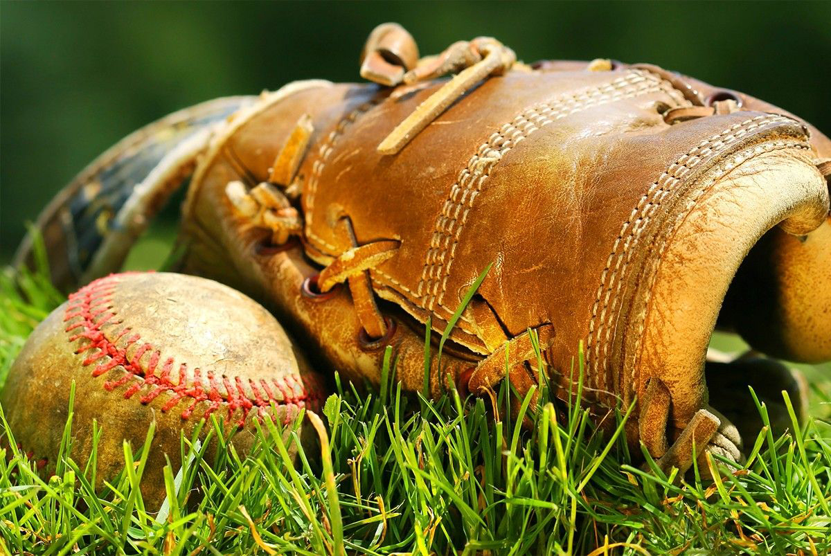 baseball glove and baseball in grass